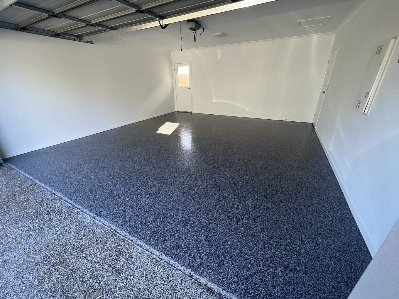 Navy blue flake epoxy floor running out to a speckled driveway apron