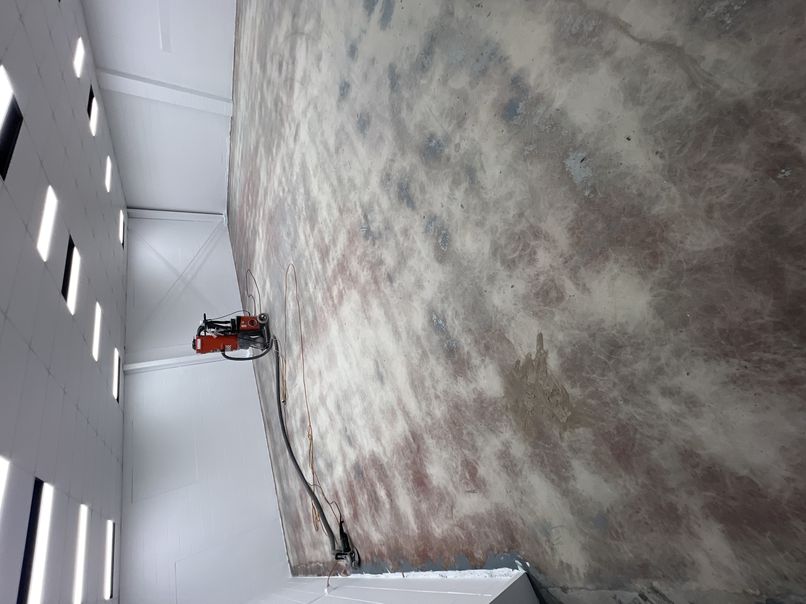 A concrete grinder part-way through prepping a large shed slab for epoxy