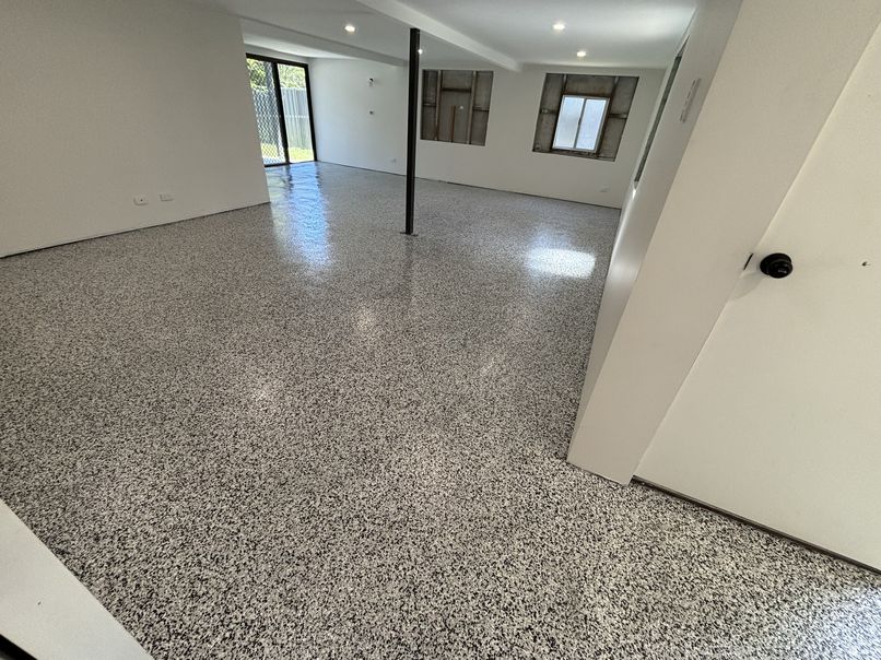 Light grey flake epoxy flooring through an open-plan converted garage space