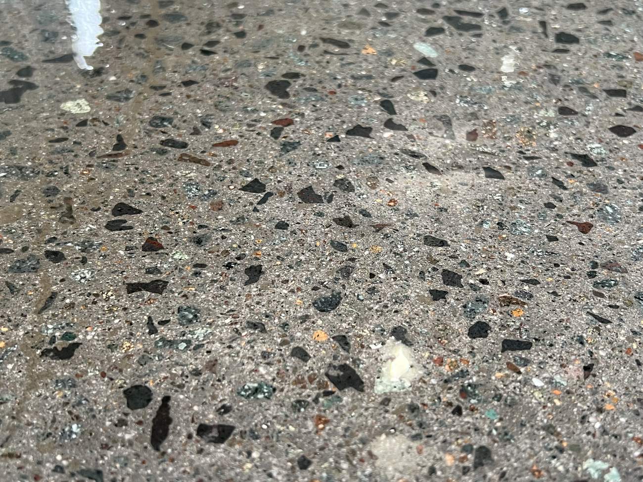 Close-up of cured epoxy flake and clear sealer on a residential driveway coating