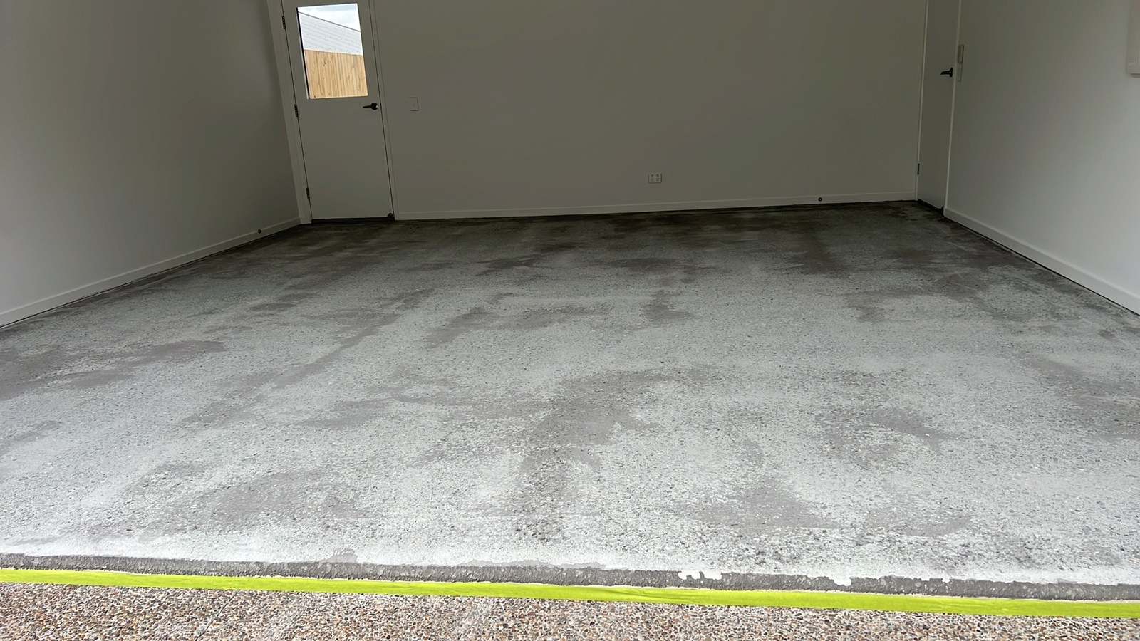 A single home garage ground back to bare concrete and taped off, ready for epoxy, Sunshine Coast