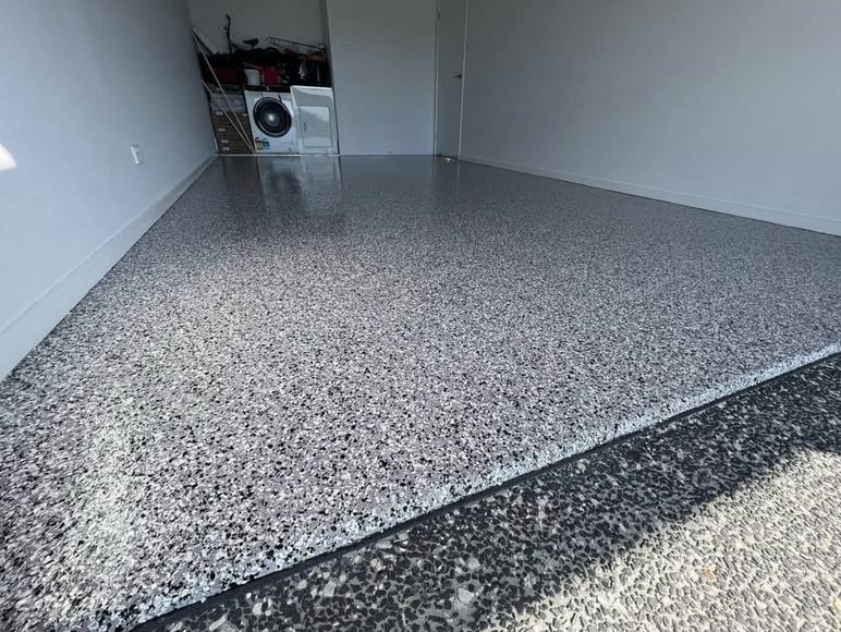 A garage finished in grey, black and white flake epoxy running out to the driveway