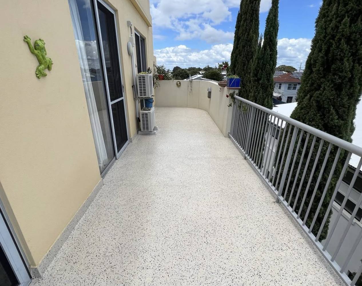 Cream flake epoxy resurfacing on a first-floor balcony with a metal balustrade